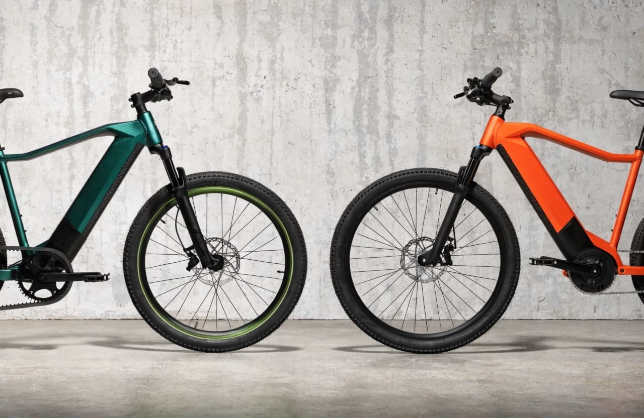 An e-bike with a belt drive system next to one with a traditional chain drive.